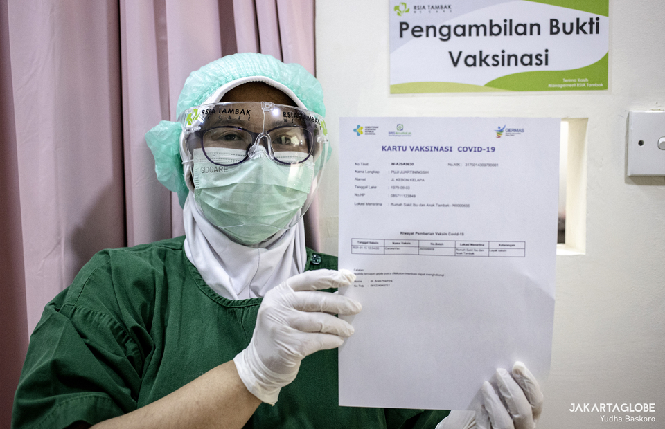 A health worker shows a COVID-19 vaccination card at RSIA Tambak in South Jakarta on Jan, 15, 2021. (JG Photo/Yudha Baskoro)