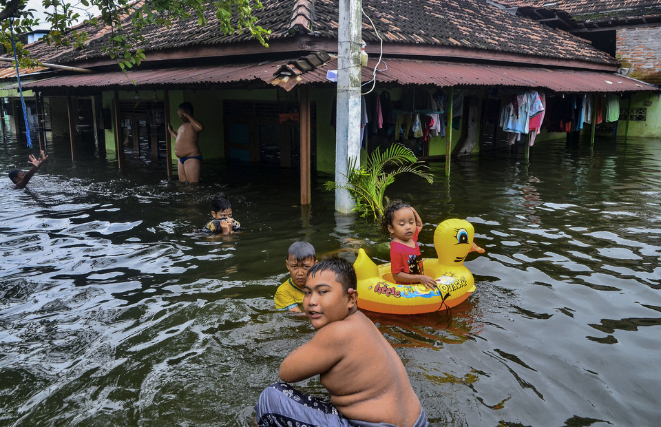 Sejumlah anak bermain di genangan banjir, di Dukuh Tanggulangin, Desa Jati Wetan, Jati, Kudus, Jawa Tengah, Senin (8/2/2021). Menurut data dari Badan Penanggulangan Bencana Daerah (BPBD) setempat, banjir dengan ketinggian hingga 170 centimeter yang merendam 13 desa di kecamatan Mejobo, Jati dan Undaan lebih dari sepekan akibat curah hujan tinggi serta meluapnya sungai Lusi dan Wulan itu menyebabkan sebanyak 17.614 jiwa terdampak dan 4.420 rumah terendam serta 576 warga mengungsi. ANTARA FOTO/Yusuf Nugroho/hp.