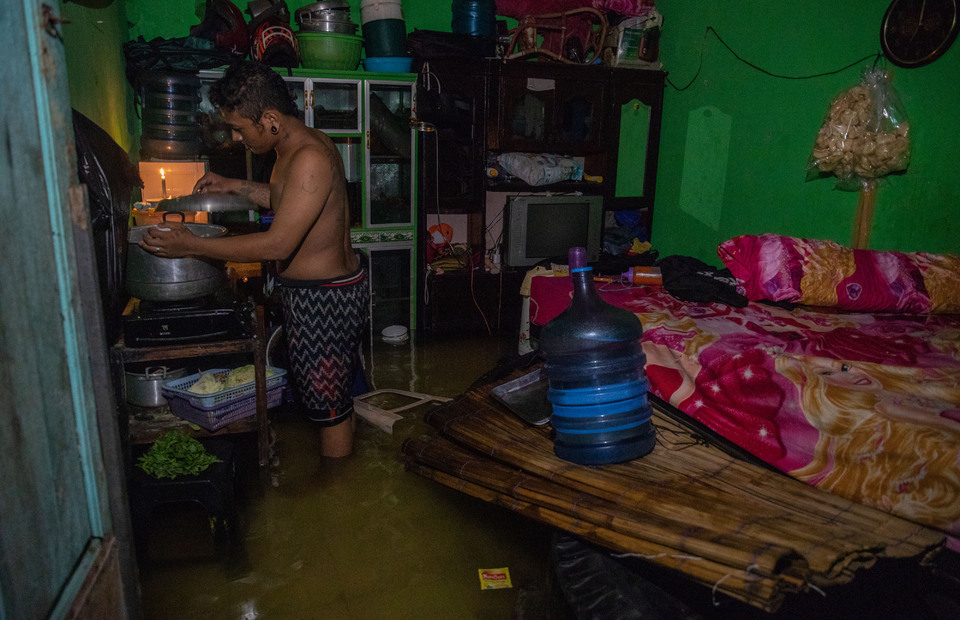 Seorang warga memasak di dalam rumahnya yang terendam banjir di Kelurahan Tanjung Mas, Semarang, Jawa Tengah, Sabtu (6/2/2021). Menurut data yang dihimpun Badan Penanggulangan Bencana Daerah (BPBD) Kota Semarang, sekitar 76 kelurahan yang tersebar di 10 kecamatan di Kota Semarang terendam banjir akibat curah hujan tinggi sejak Jumat (5/2) malam. ANTARA FOTO/Aji Styawan/wsj.