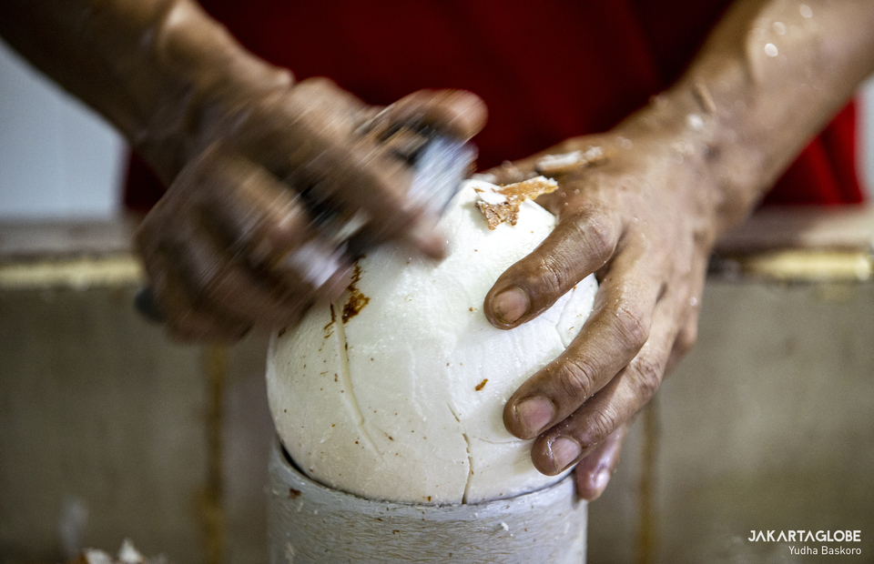 A worker peels a coconut before grind and mix it with various types of herbs and plants to make a blended spices at Tebet traditional market in South Jakarta on Feb, 8, 2021. (JG Photo/Yudha Baskoro)