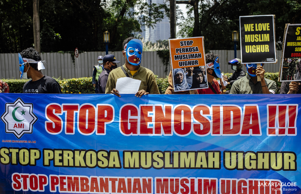 Protesters carry placard that reads stop genocide during during protest in front of Embassy of the People