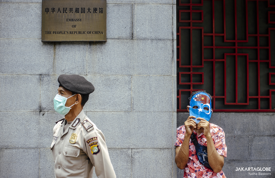 Protester stands beside an Indonesian police personnel during protest in front of Embassy of the People
