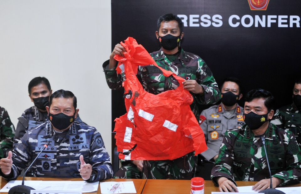 A Navy officer shows an orange vest pulled from the debris of sunken KRI Nanggala-402 submarine as Navy Chief of Staff Admiral Yudo Margono, left, speaks in a news conference in Bali on April 25, 2021. The submarine was found with the help of a Singapore naval ship four days after it sank on April 21. (Antara Photo/Fikri Yusuf)