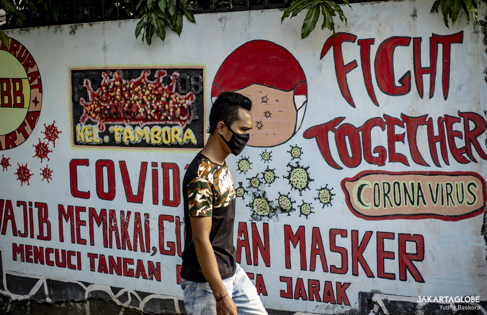 A man walks in front of Covid-19 mural at Tambora area in Central Jakarta on June 3, 2021. (JG Photo/Yudha Baskoro)