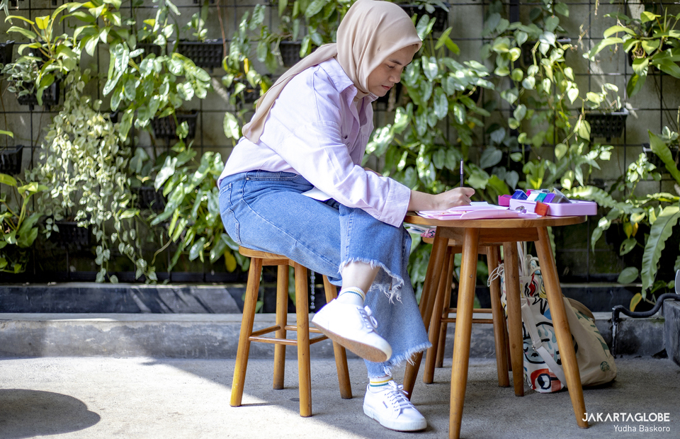 Faza sits quietly as she draws using paint brush at a coffee shop in Depok, West Java on June 5, 2021. (JG Photo/Yudha Baskoro)