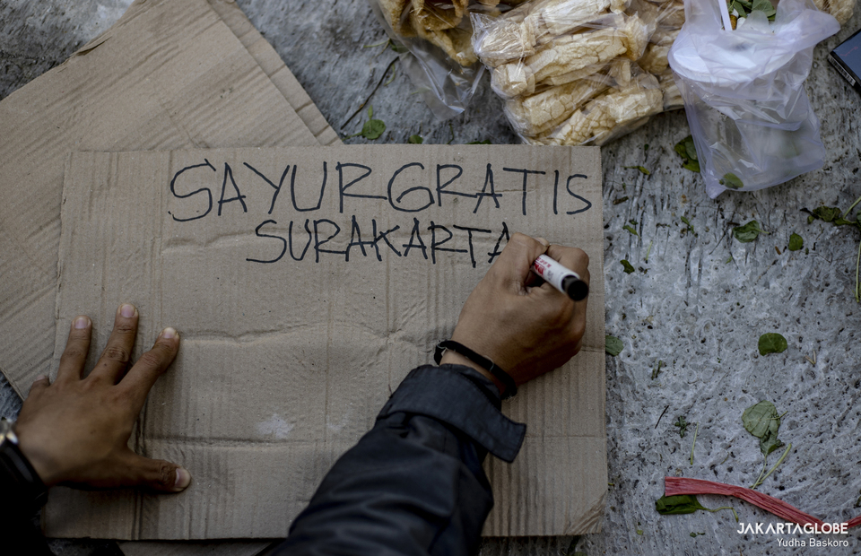 A volunteer writes sayur gratis surakarta on a piece of cardboard at Pasar Legi, in Solo, Central Java on July 31, 2021. (JG Photo/Yudha Baskoro)