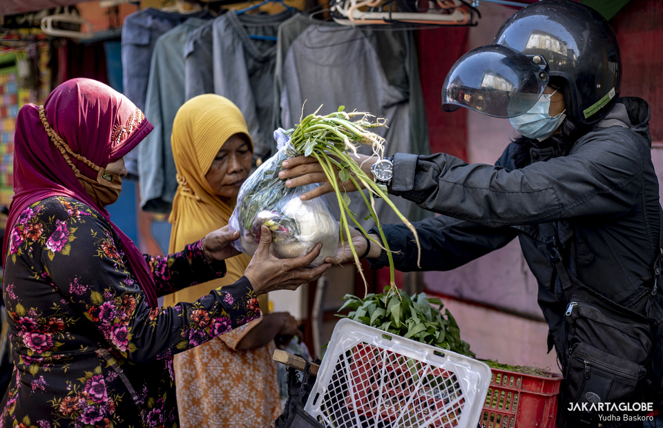 A volunteer of Sayur Gratis Surakarta gives a plastic of vegetables to a woman at Solo, Central Java on July 31, 2021. (JG Photo/Yudha Baskoro)