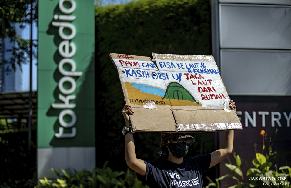 Protester carries placard in front of Tokopedia tower building in South Jakarta on September 9, 2021. (JG Photo/Yudha Baskoro)
