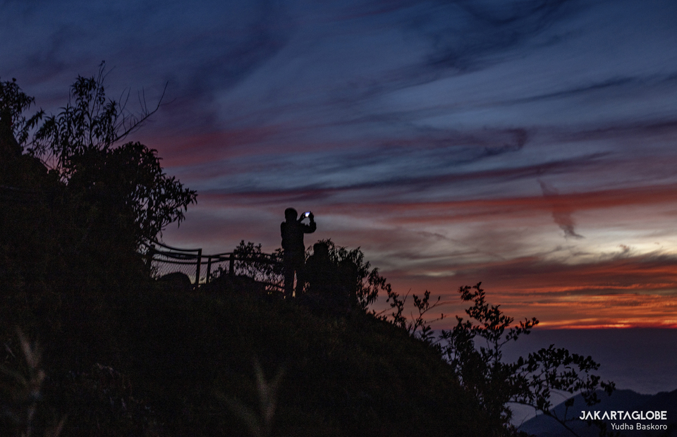 A man takes a photo during golden sunrise at Sikunir Hill at Dieng Plateu in Central Java on October 2, 2021. (JG Photo/Yudha Baskoro)
