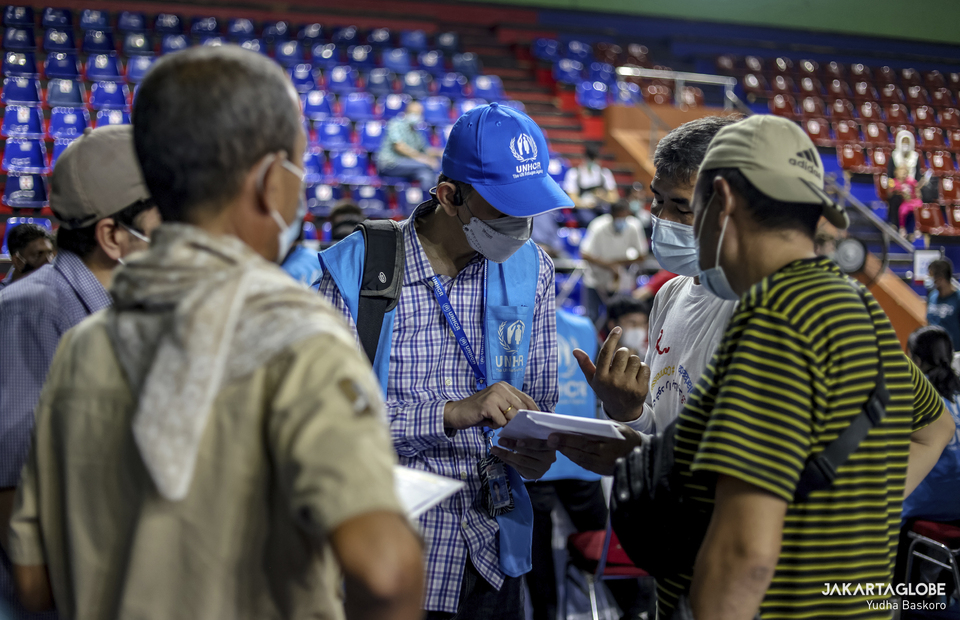 UNHCR worker gives an assist to refugees and asylum seekers during a mass vaccination program for refugees and asylum seekers at Bulungan sports hall in South Jakarta on October 7, 2021. (JG Photo/Yudha Baskoro)