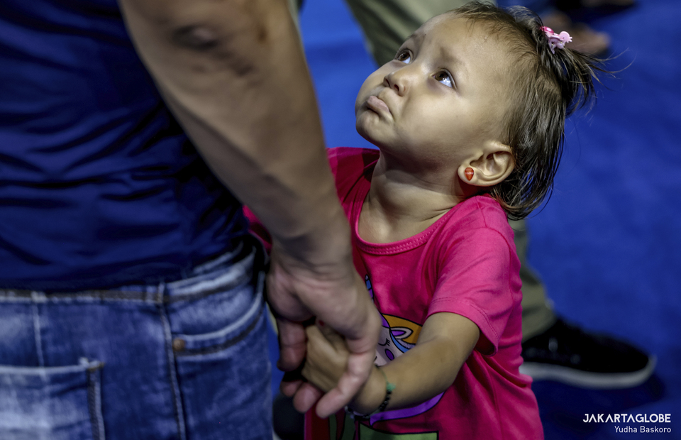 A child reacts as she waits her parent to receive Covid-19 vaccine during a mass vaccination program for refugees and asylum seekers at Bulungan sports hall in South Jakarta on October 7, 2021. (JG Photo/Yudha Baskoro)