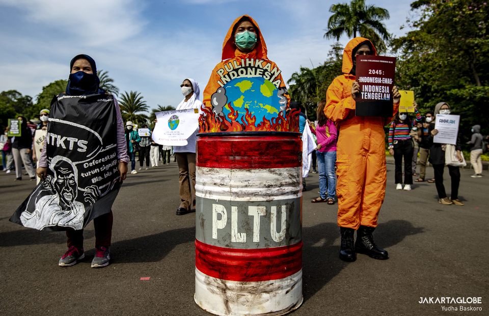 An environmental activists wear forestry worker costum during a protest against climate change in front of the Arjuna Wijaya horse statue in Central Jakarta on November 5, 2021. (JG Photo/Yudha Baskoro)