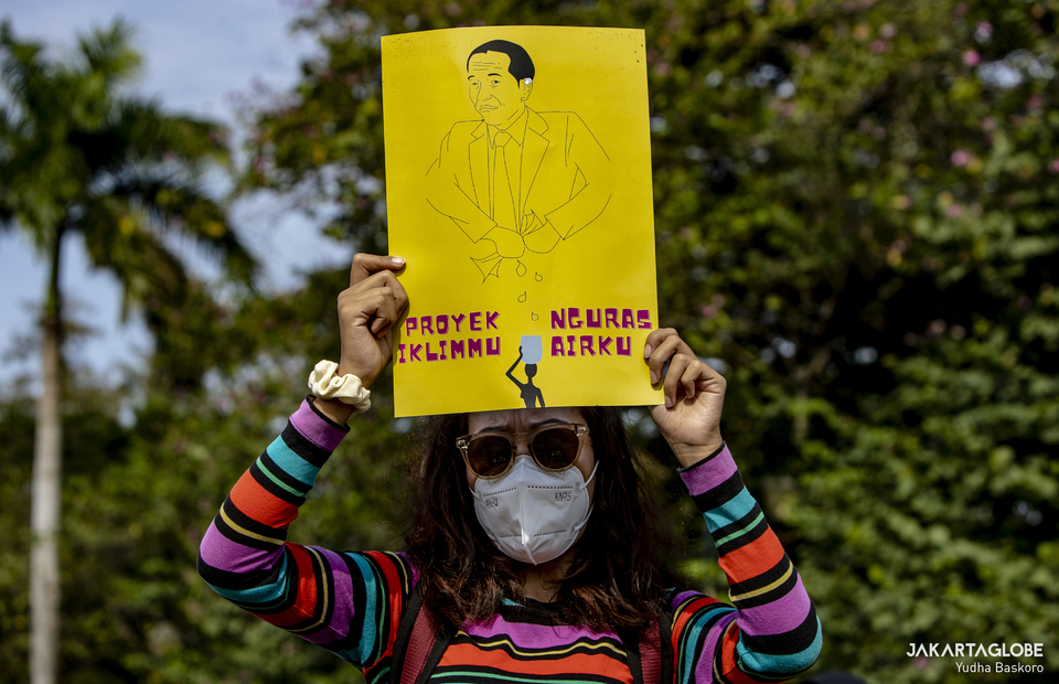 Environmental activist carries placard during a protest against President