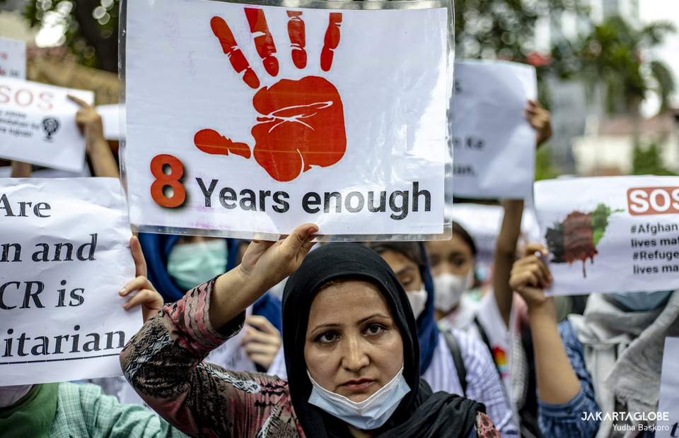A protester carries a placard that reads 8 years is enough during protest in front UNHCR building in Central Jakarta on November 15, 2021. (JG Photo/Yudha Baskoro)