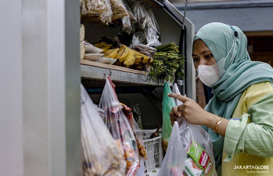 Yuni picks up some item for her customer at Srengseng Sawah, South Jakarta on January 20, 2022. (JG Photo/Yudha Baskoro)