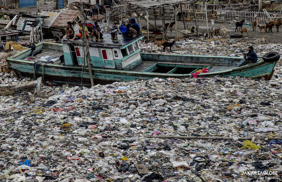 Residents sit on an abandoned boat in the middle of sea of garbage at Kali Baru Village, Cilincing, North Jakarta on March 2, 2022. (JG Photo/Yudha Baskoro)