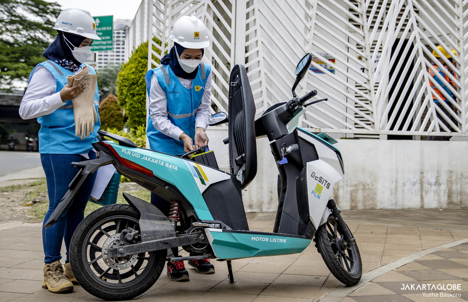 Two woman technician put a battery inside a electric bike in front of electrical substation in Jalan M.H. Thamrin, Central Jakarta on April 20, 2022. (JG Photo/Yudha Baskoro)