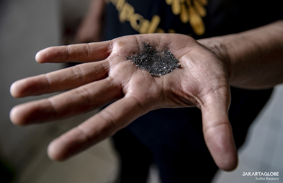 A man holds a coal ash and dust debris at Rusunawa Marunda, Cilincing, North Jakarta on April 25, 2022. (JG Photo/Yudha Baskoro)