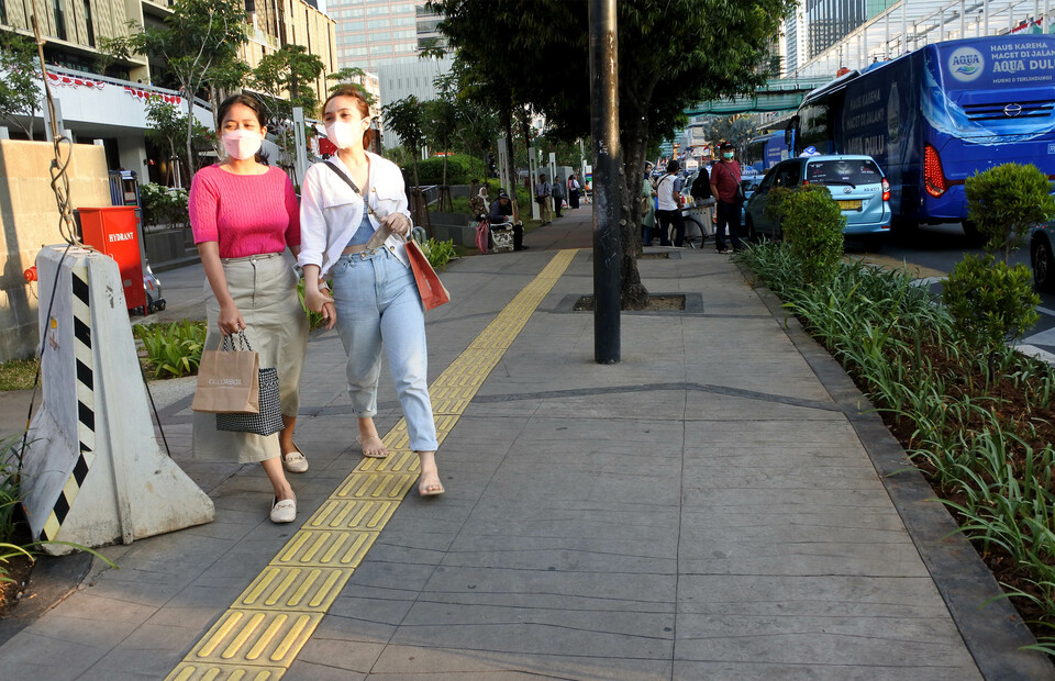 Two women walk along the sidewalk in front of Sarinah Shopping Center on Jalan Thamrin, Central Jakarta, on August 18, 2022. (BeritasatuPhoto/Joanito De Saojoao)