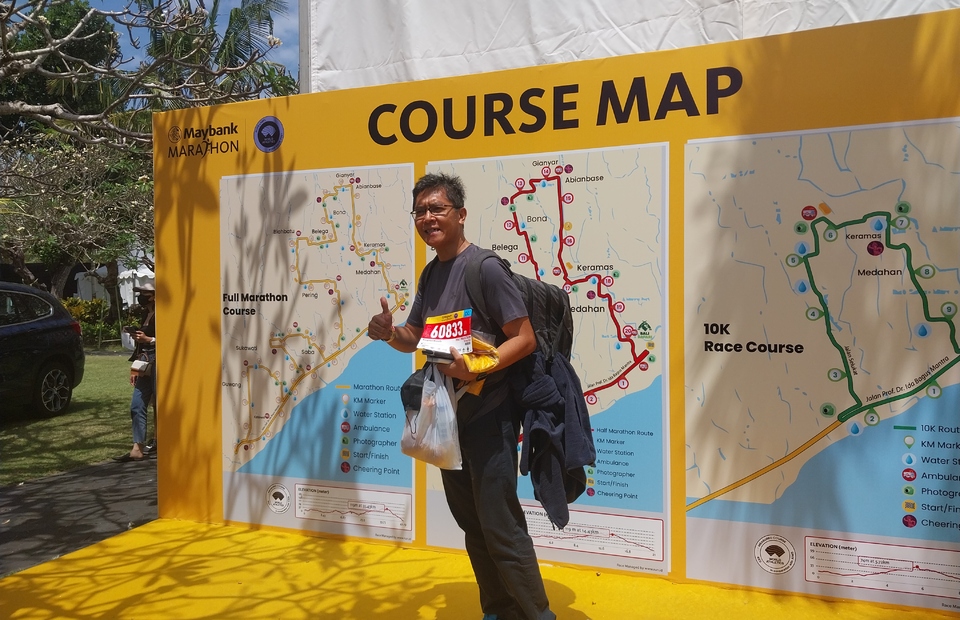 A man takes a picture with his Maybank Marathon 2022 bib number at Taman Bhagawan in Bali on Aug. 26, 2022. The red-colored bib shows he will compete in the half-marathon. (JG Photo/Jayanty Nada Shofa)	