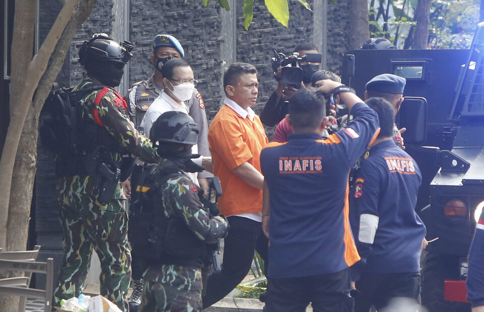 Disgraced police general Ferdy Sambo, dressing in an orange detainee suit, walks at the murder scene during the reenactment of a policeman murder case on Duren Tiga housing complex, South Jakarta, on August 30, 2022. (Beritasatu Photo/Ruht Semiono)