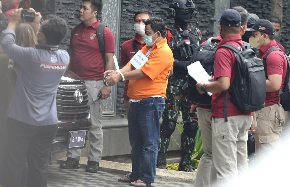 Murder suspect Kuat Maruf, center, arrives at Duren Tiga housing complex in South Jakarta on August 30, 2022, to reenact the murder of police officer Nofriansyah Yosua. (Beritasatu Photo/Ruht Semiono) 