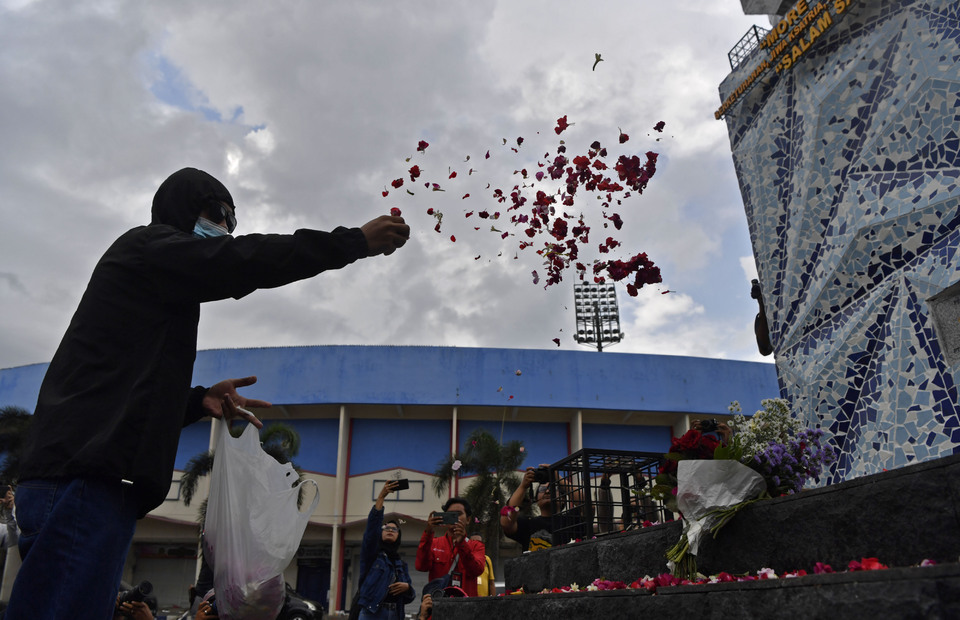 A man strews flowers near the Kanjuruhan Stadium in the East Java town of Malang on October 2, 2022, to pay tribute to the victims of a riot involving Arema Football Club supporters that killed at least 174 people a day earlier. (Antara Photo/Zabur Karuru)