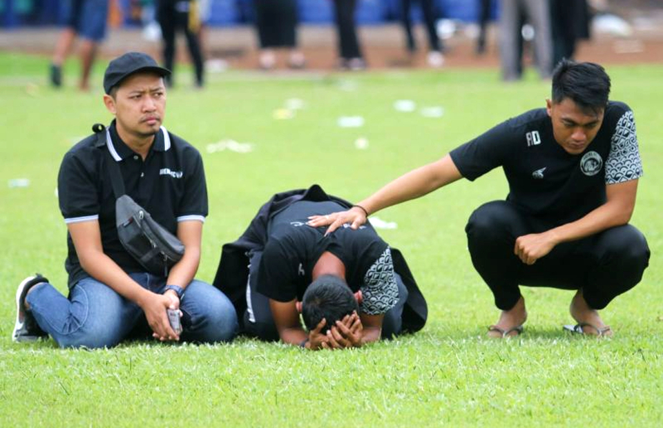 Three players of Arema Football Club pray at the Kanjuruhan Stadium in the East Java town of Malang on Oct. 3, 2022, paying tribute to at least 131 people who died during post-match clashes between fans and security officials in the stadium two days earlier. (Antara Photo)