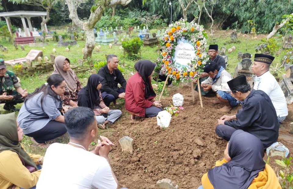 Friends and family members pray at the grave of police officer Fajar Yoyok Pujiono in Trenggalek, East Java, on Oct. 2, 2022. The officer was among at least 131 people who died during post-match clashes between fans and security officials at the Kanjuruhan Stadium in Malang a day earlier. (Antara Photo)