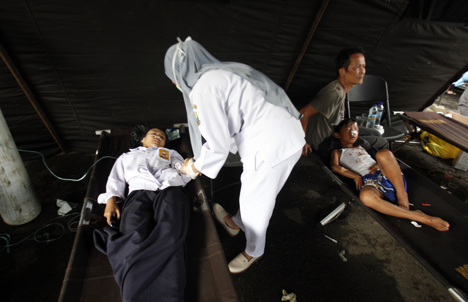 An injured man receives first aid treatment outside of municipally-owned Cimacan Hospital after an earthquake in the West Java district of Cianjur on November 21, 2022. (Antara photo/Yulius Satria Wijaya)