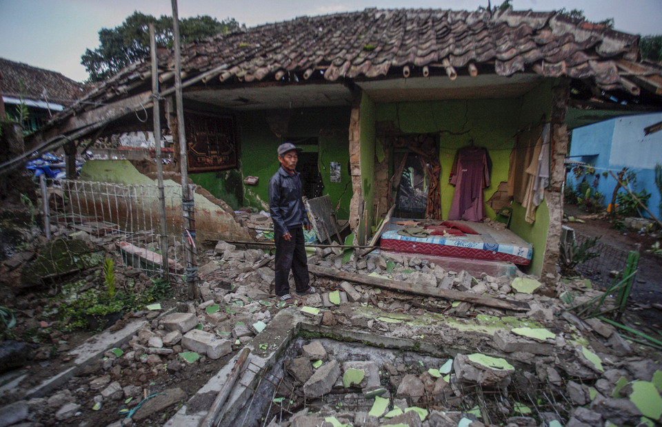 A man stands in front of a collapsed home after an earthquake that rocked the West Java town of Cianjur on November 21, 2022. (Antara photo//Yulius Satria Wijaya)